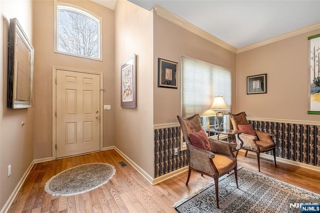 entryway with light wood-style floors, visible vents, ornamental molding, and baseboards