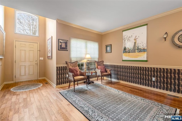 living area featuring light wood-type flooring, visible vents, baseboards, and crown molding