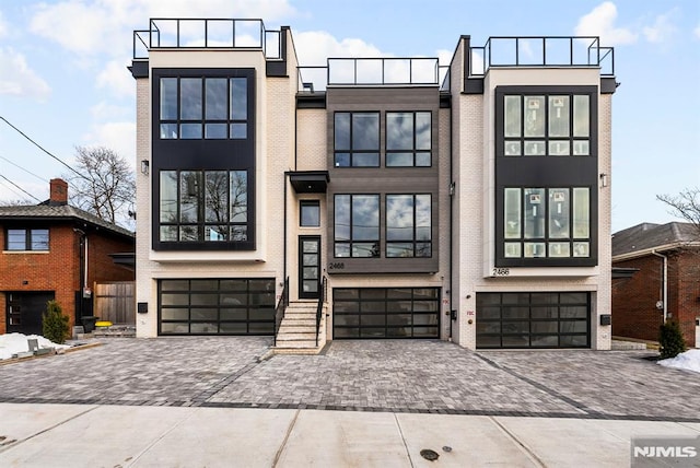 view of front of home with an attached garage, stucco siding, decorative driveway, and brick siding