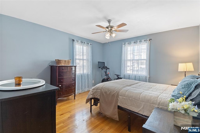 bedroom with multiple windows, light wood-style flooring, and a ceiling fan