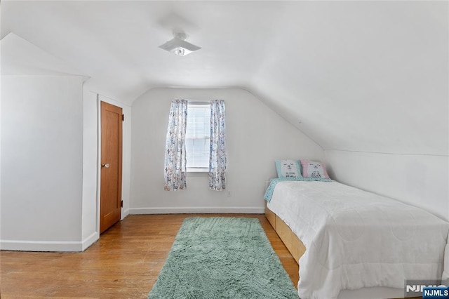 bedroom featuring lofted ceiling, baseboards, and light wood finished floors