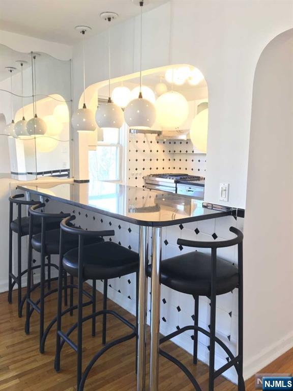 kitchen with arched walkways, stove, a breakfast bar area, and wood finished floors