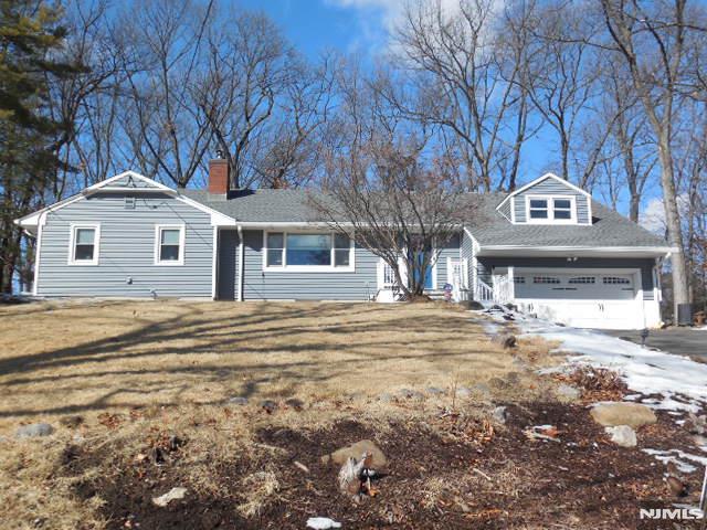 view of front of home featuring a garage, aphalt driveway, a chimney, and a front lawn