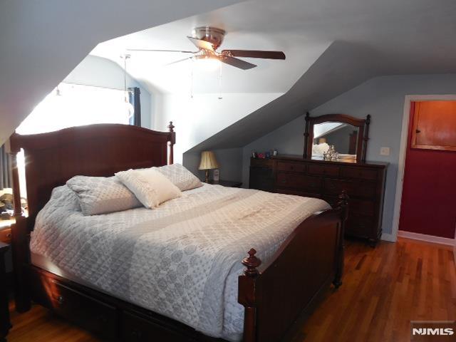 bedroom with lofted ceiling, wood finished floors, a ceiling fan, and baseboards