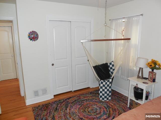 interior space with a closet, visible vents, and wood finished floors