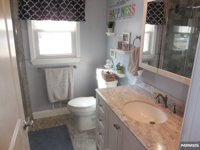 bathroom featuring vanity, a shower stall, toilet, and baseboards