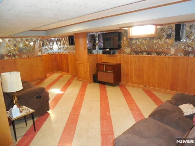 below grade area with wainscoting, wooden walls, and tile patterned floors