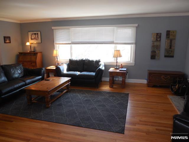 living room featuring crown molding, wood finished floors, and a healthy amount of sunlight