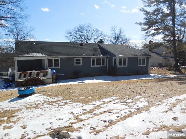 snow covered back of property featuring a wooden deck