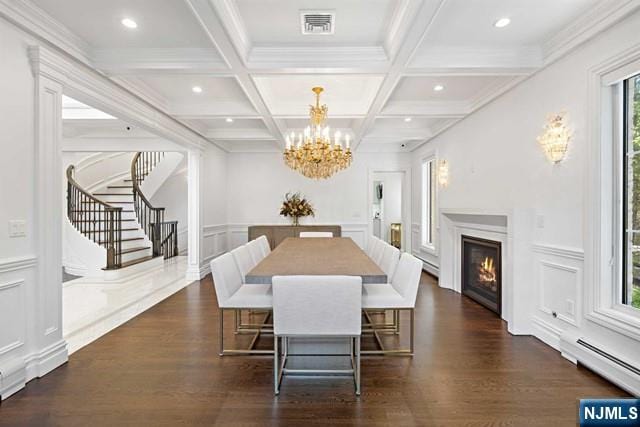 dining room with beamed ceiling, visible vents, a decorative wall, baseboard heating, and stairs