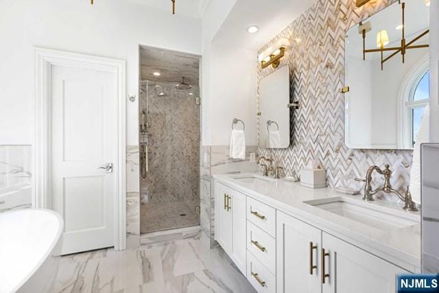 full bathroom featuring double vanity, a stall shower, a freestanding bath, a sink, and marble finish floor