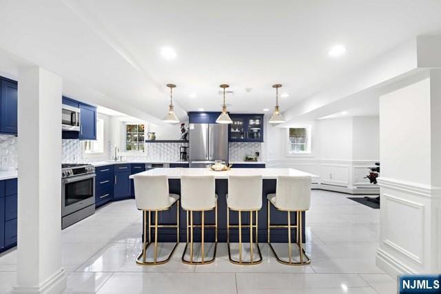 kitchen featuring a breakfast bar area, decorative backsplash, a decorative wall, stainless steel appliances, and blue cabinets