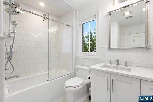 bathroom featuring visible vents, bath / shower combo with glass door, vanity, and toilet