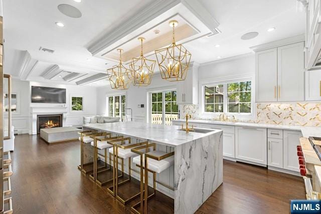 kitchen featuring light stone counters, plenty of natural light, a lit fireplace, open floor plan, and tasteful backsplash