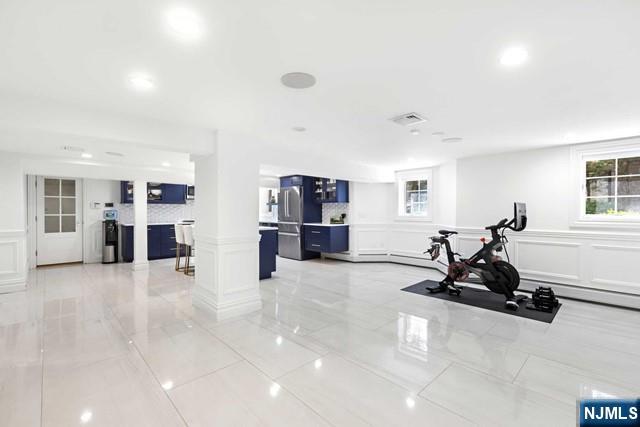 workout room with a wealth of natural light, a decorative wall, visible vents, and ornate columns