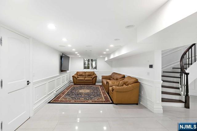 living room with stairway, a decorative wall, and recessed lighting