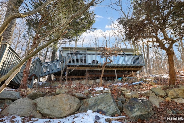 rear view of property featuring a wooden deck and stairs