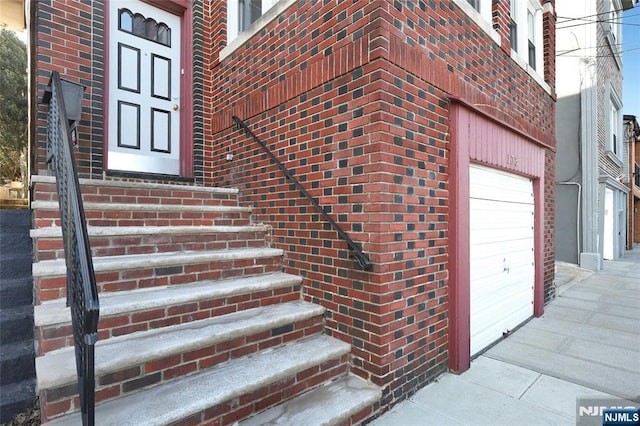 entrance to property with a garage and brick siding