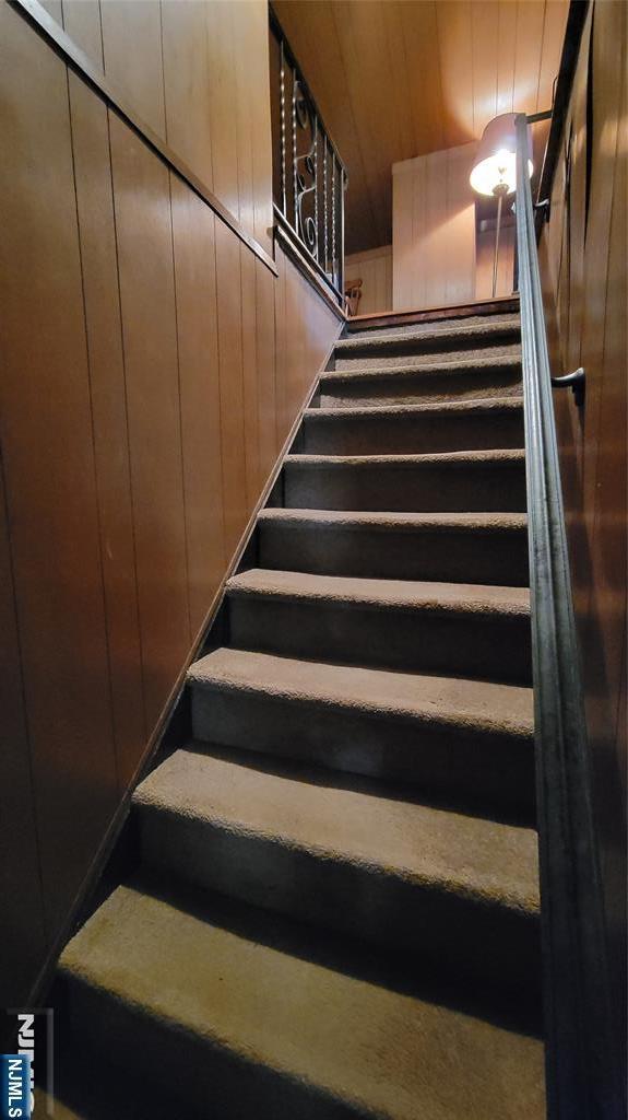 staircase featuring wooden walls