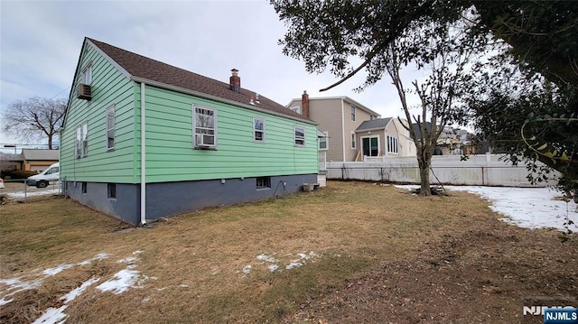 view of home's exterior with a chimney, fence, and a yard