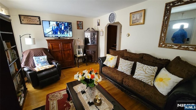 living room featuring light wood-style flooring, stairs, and arched walkways