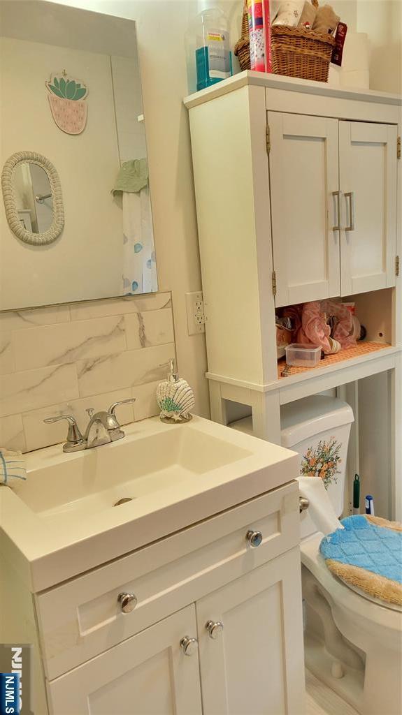 bathroom with toilet, backsplash, and vanity