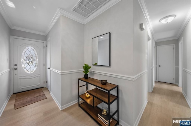 entryway with ornamental molding, light wood-type flooring, visible vents, and baseboards