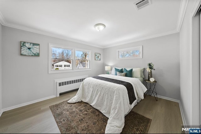 bedroom featuring ornamental molding, radiator, baseboards, and wood finished floors