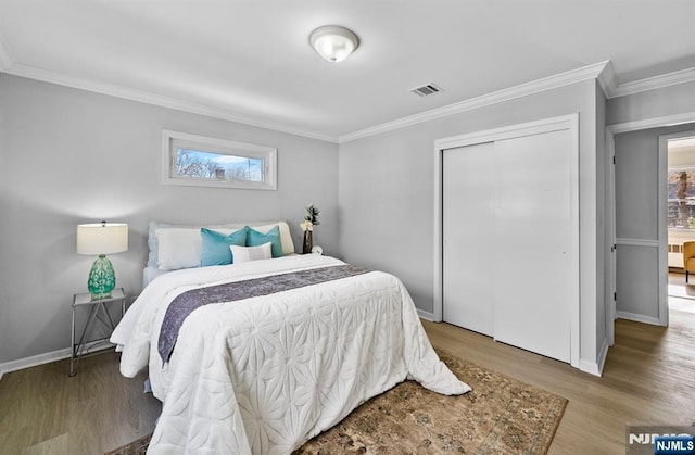 bedroom with wood finished floors, visible vents, crown molding, and multiple windows