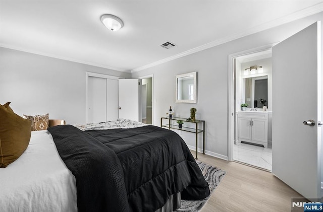 bedroom with light wood finished floors, a closet, visible vents, ornamental molding, and baseboards