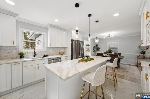 kitchen featuring white cabinets, a kitchen island, light stone counters, appliances with stainless steel finishes, and a sink