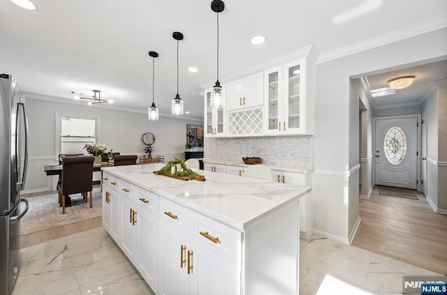 kitchen with a kitchen island, white cabinetry, marble finish floor, freestanding refrigerator, and glass insert cabinets