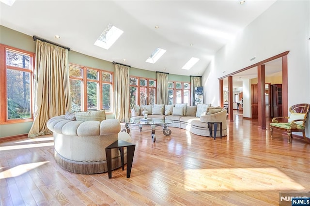 living area with lofted ceiling with skylight and wood finished floors