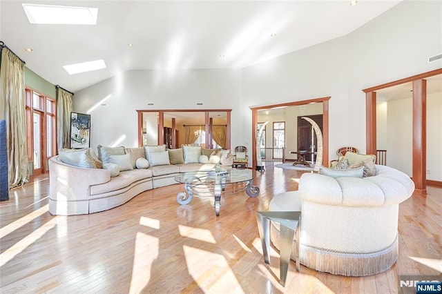 living room with wood finished floors, a healthy amount of sunlight, and lofted ceiling with skylight