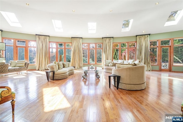 living area with light wood finished floors and lofted ceiling with skylight