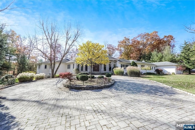 view of front facade featuring curved driveway and a front yard