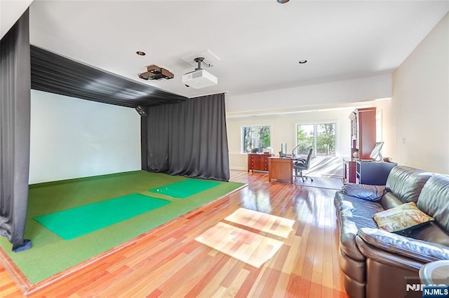 game room with hardwood / wood-style flooring and golf simulator