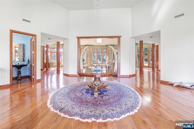 entryway featuring visible vents, a towering ceiling, baseboards, and wood finished floors