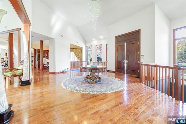 foyer featuring an inviting chandelier, light wood finished floors, and high vaulted ceiling