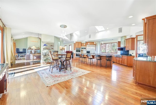 dining area with light wood finished floors, visible vents, and lofted ceiling