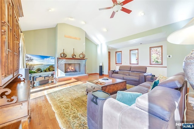 living area with a fireplace, lofted ceiling, wood finished floors, and ceiling fan