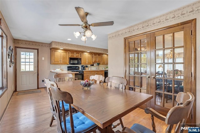 dining space with light wood-style floors, french doors, wallpapered walls, and a ceiling fan