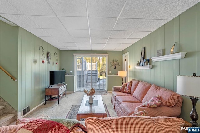 carpeted living area with visible vents, stairway, and a drop ceiling