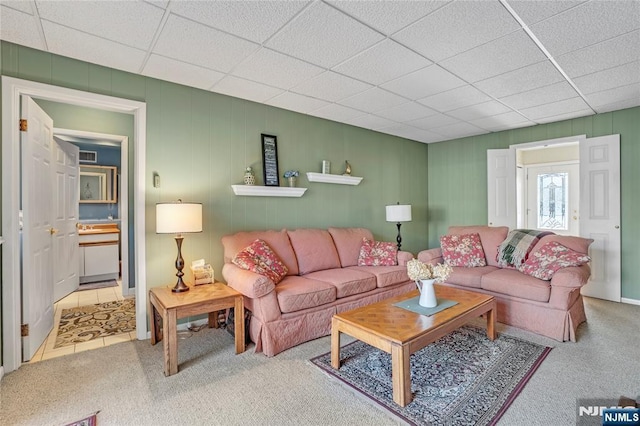 carpeted living area featuring tile patterned flooring and a paneled ceiling