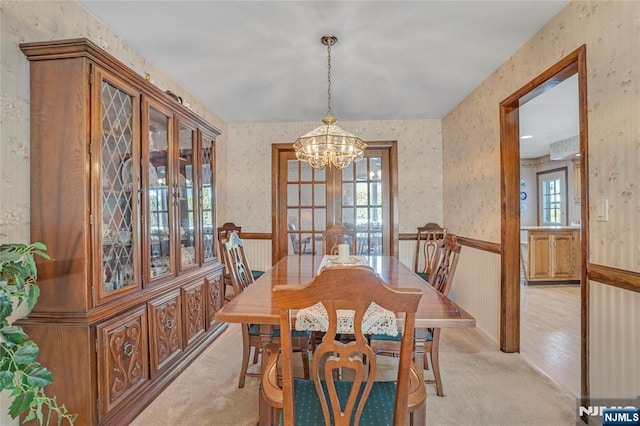 dining space featuring a wainscoted wall, plenty of natural light, light carpet, and wallpapered walls