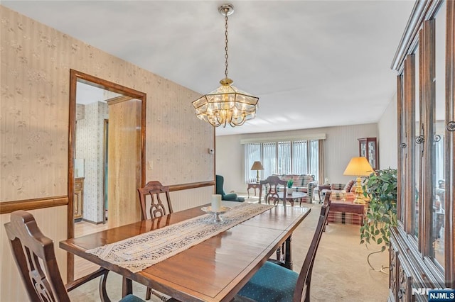 carpeted dining space featuring wallpapered walls and a chandelier