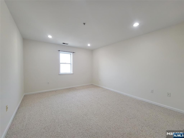 empty room featuring baseboards, light carpet, visible vents, and recessed lighting