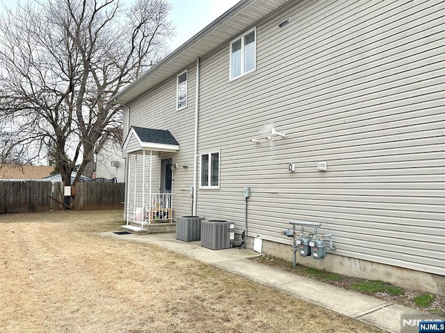 rear view of house with a yard, central AC, and fence