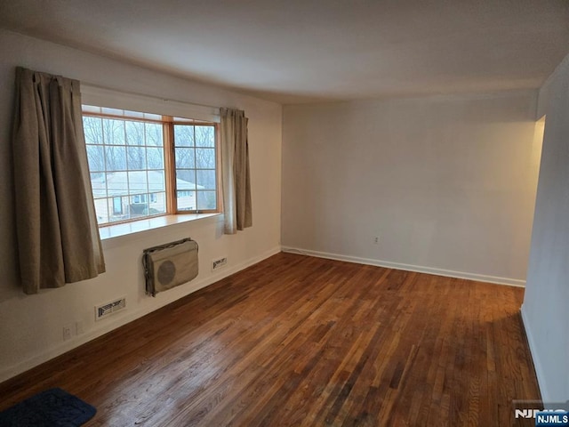 unfurnished room with dark wood-style floors, baseboards, and visible vents