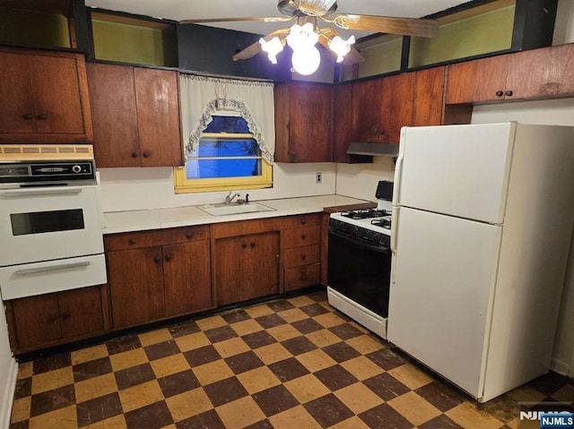 kitchen featuring dark floors, a warming drawer, light countertops, white appliances, and under cabinet range hood